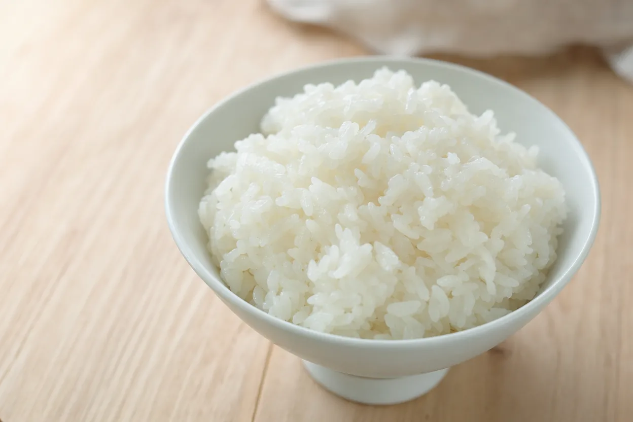 Gros plan d'un bol de riz blanc bien cuit nature sur un plan de travail en bois